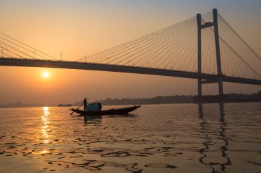 Siluet günbatımı Vidyasagar Bridge Hooghly Nehri üzerinde bir balıkçı teknesi ile.
