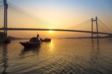 Ahşap tekneler nehrinde Hooghly, Kalküta, Hindistan ile Vidyasagar köprü üzerinde doğal günbatımı.