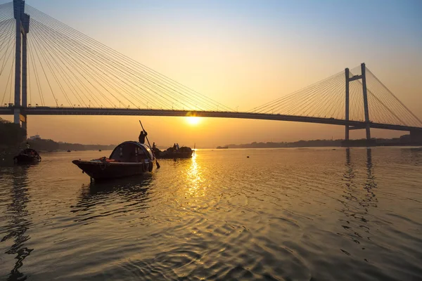 Pôr-do-sol cênico sobre a ponte Vidyasagar com barcos de madeira no rio Hooghly, Kolkata, Índia . — Fotografia de Stock