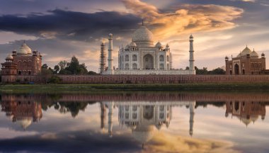 Taj Mahal Yamuna nehrinde canlı gökyüzü ve su yansıması ile gün batımında.