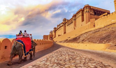 Turistler gün batımında Amer Kalesi Jaipur Rajasthan 'da fil gezintisinin keyfini çıkarıyorlar..