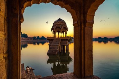 Gadisar Gölü (Gadi Sagar) Jaisalmer Rajasthan 'da antik tapınaklar ve gündoğumunda arkeolojik kalıntılarla