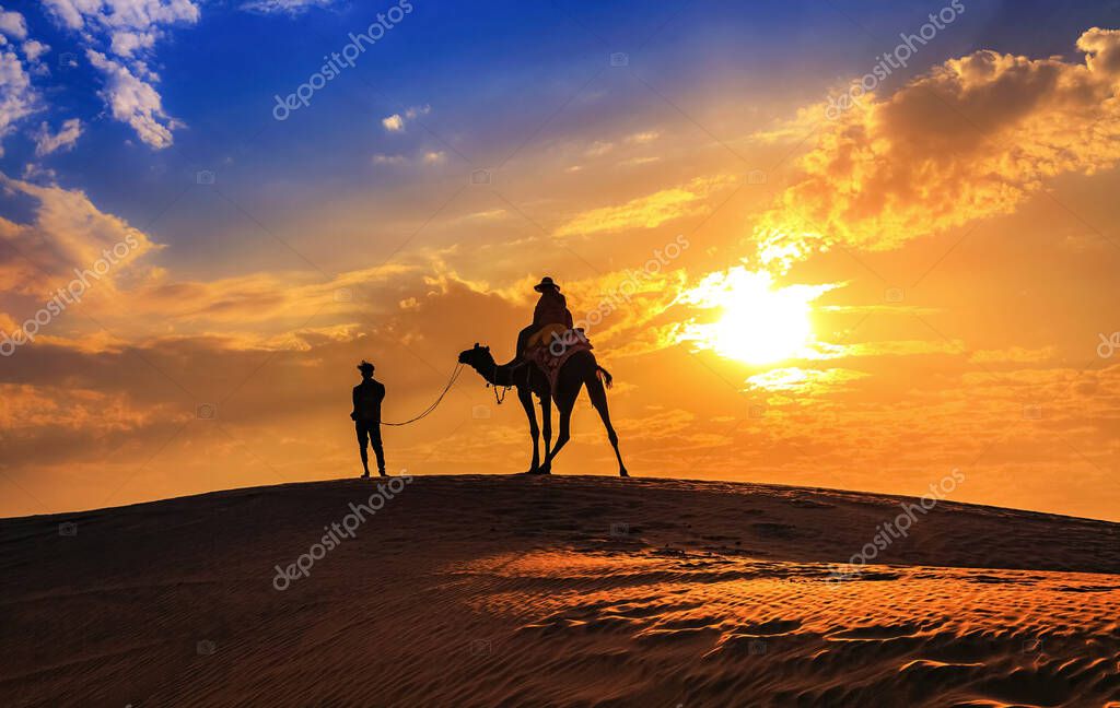 Desert sunset at Jaisalmer Rajasthan with tourist on camel in silhouette effect and moody sky.
