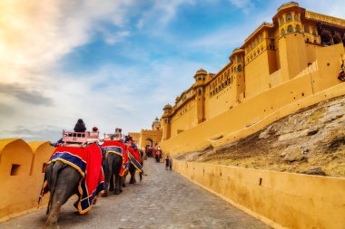 Jaipur, Rajasthan, Hindistan, 11 Aralık 2017: Karamsar gökyüzü ile tarihi Amer Kalesi Jaipur 'da turistlerle süslenmiş Hint filleri.