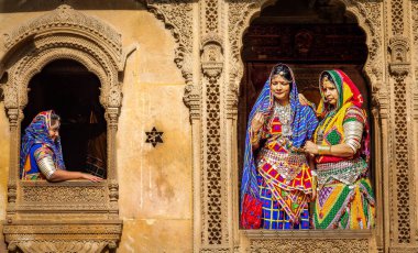 Jaisalmer, Rajasthan, Hindistan, 14 Aralık 2017: Geleneksel Rajasthani kıyafeti ve mücevher giymiş Hintli kadınlar Patwon ki haveli miras binasında poz veriyorlar Jaisalmer.