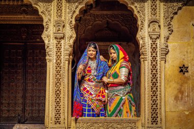 Jaisalmer, Rajasthan, Hindistan, 14 Aralık 2017: Geleneksel Rajasthani kıyafeti ve mücevher pozu giymiş kadın turistler Patwon ki haveli miras binası Jaisalmer, Rajasthan, Hindistan