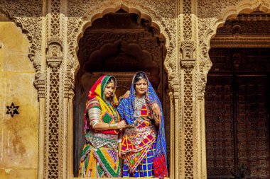 Jaisalmer, Rajasthan, Hindistan, 14 Aralık 2017: Jaisalmer Rajasthan 'daki Patwon ki haveli miras binasında geleneksel Rajasthani kıyafeti ve mücevher pozu giymiş kadın turistler. 