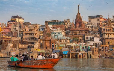 Varanasi, Hindistan, 13 Ekim 2017: Turistler antik mimariye sahip tarihi Varanasi şehrine bakan Ganj Nehri üzerinde tekne turunun keyfini çıkarıyorlar.