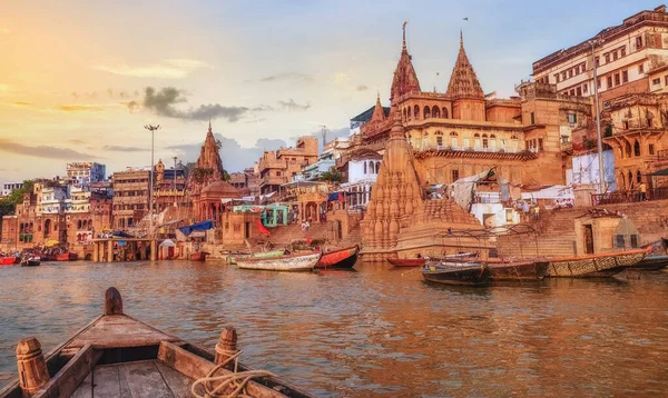 Varanasi Ganges nehir ghat ile antik şehir mimarisi günbatımında nehirde bir tekne görüntüsü.