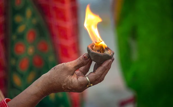 インドのヒンドゥ教徒の女性がヴァラナシ族の儀式の一環としてガンジス川で提供する神聖な火で手作りの粘土ランプを保持する手インド — ストック写真