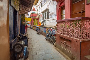 Varanasi, Hindistan, 13 Ekim 2017: Tipik Varanasi dar sokakları, eski yıpranmış binalarla antik tapınaklar ve her iki tarafa da iki tekerlek park edilmiş..