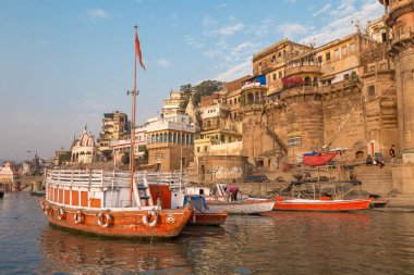 Varanasi, Hindistan, 13 Ekim 2017: Ganj nehir kıyısı boyunca antik mimari binaları ve turist tekneleri bulunan tarihi Varanasi kenti.