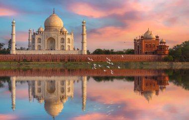 Taj Mahal Agra tarihi ortaçağ beyaz mermer heykeli günbatımında su yansıması ve karamsar gökyüzü