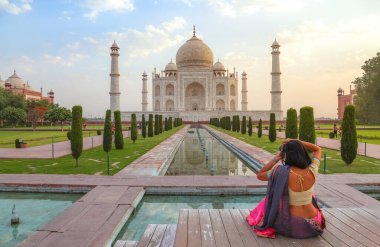 Taj Mahal Agra gün doğumunda kadın turistle birlikte tarihi anıtın fotoğraflarını çekiyor.