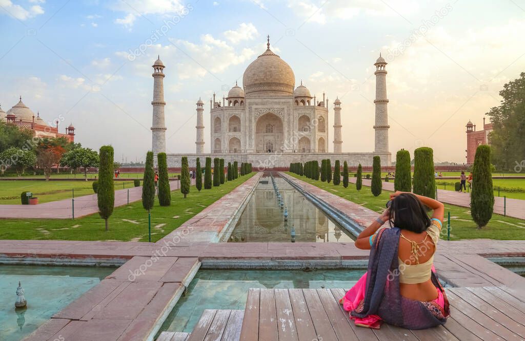 Taj Mahal Agra at sunrise with female tourist clicking photographs of the historic monument