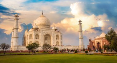 Taj Mahal gün batımında Agra, Uttar Pradesh, Hindistan 'da turistlerle bitişik bahçe manzaralı. Taj Mahal, UNESCO Dünya Mirası olarak belirlenmiş beyaz mermer bir mozoledir.