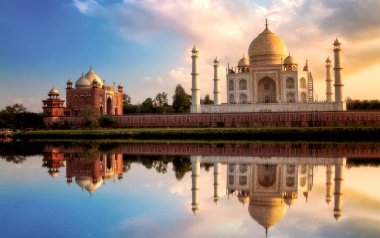 Taj Mahal tarihi anıtı günbatımında Mehtab Bagh 'tan, Hindistan' ın Agra kentindeki Yamuna nehrinde ayna yansıması ile görülmektedir.