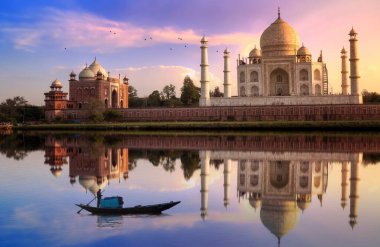 Taj Mahal tarihi mozolede gün batımında kasvetli gökyüzü ve ahşap tekne ile Agra, Hindistan 'da Yamuna nehrinde.