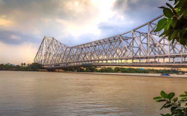 Howrah bridge on river Hooghly at sunset with dark monsoon clouds