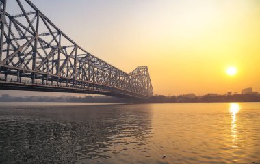 Güneş doğarken hüzünlü gökyüzü ile tarihi Howrah Köprüsü. Howrah Köprüsü, Kolkata, Hindistan 'da Hooghly nehri üzerinde bir kantilever köprüdür..