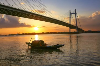 Günbatımında Ganj nehrinde inşa edilen Vidyasagar Setu olarak bilinen köprü, Hindistan Kolkata 'da bir tekne manzaralı kaldı.