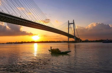 Günbatımında Ganj nehrinde inşa edilen Vidyasagar Setu olarak bilinen asma köprü, Hindistan 'ın başkenti Kolkata' da PrincepGhat 'tan görülen bir teknenin görüntüsüydü.