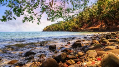 Ross Adası kayalık deniz plajı Andaman Hindistan 'da gün batımında karamsar gökyüzü. 