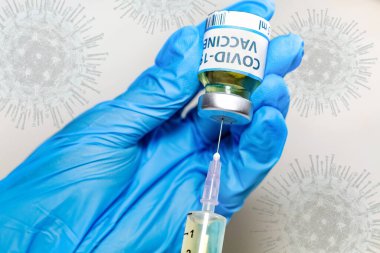 Coronavirus kavramsal görüntüsü, doktorun elinde ameliyat eldiveni, elinde şırıngayla aşı şişesi var.