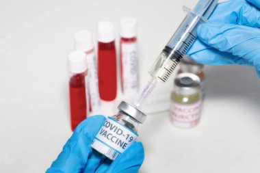 Aşı şişesinden şırınga iğnesi enjekte ederek Hindistan 'daki bir laboratuvarda Coronavirüs hastalarını tedavi eden kan örneği şişelerini inceledim.