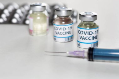 Koronavirüs hastalarının tedavisi için seçici odak noktasında şırınga ve ilaç içeren aşı şişeleri