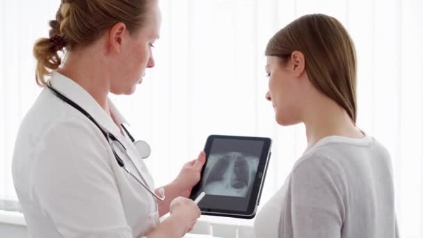 Lékař ženu ukazující X-ray na tabletu se pacientka v klinice. Profesionální lékařka v práci