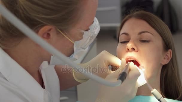Dentist treating teeth to woman patient in clinic. Female professional doctor at work. Dental checkup