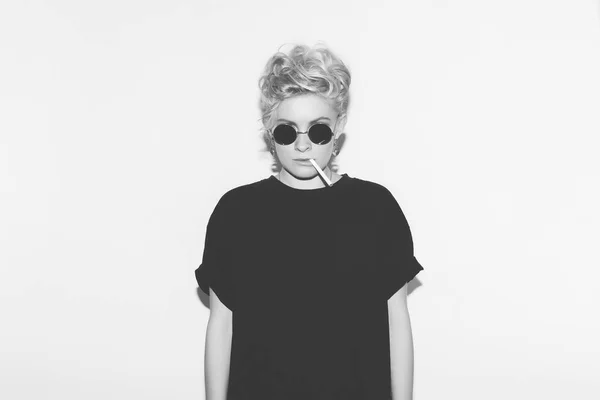 Stylish fashion sexy blonde bad girl in a black t-shirt and rock sunglasses. Dangerous rocky emotional woman. Black and white toned. White background, not isolated — Stock Photo, Image