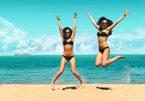 İki çekici kızlar bikinili kumsalda atlama. En iyi arkadaşlar eğlenmeye, yaz tatili Lifestyle tatil. Mutlu kadın özgürlük beyaz kum üzerinde atlama.  