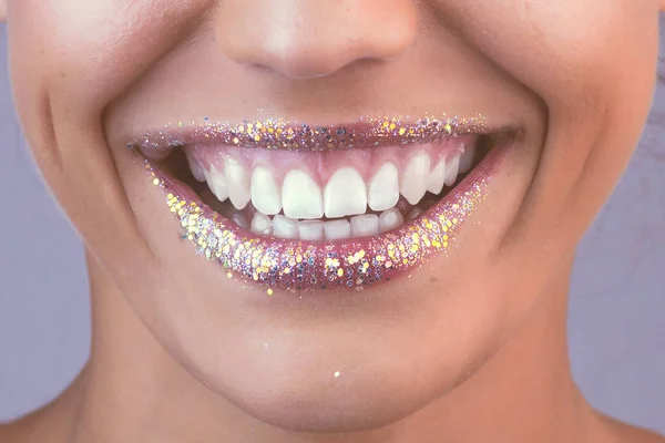 Glitter lips. Perfect teeth. Close-up shot of female laugh lips with bright lipstick in retro style colors.