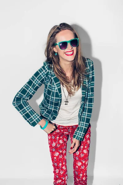 Jovem bela menina feliz hipster millennial urbana de cabelos longos em jaqueta quadriculada verde e óculos de sol se divertindo, rir e amplo sorriso com dentes perfeitos. Fundo branco. Fecha. Cor quente . — Fotografia de Stock