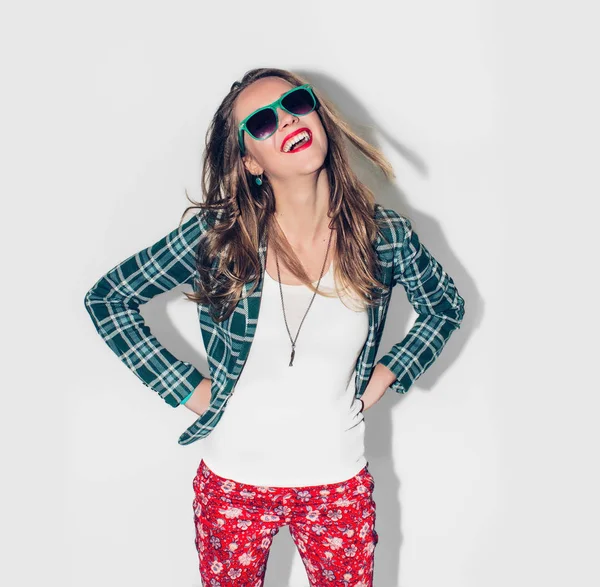 Jovem bela menina feliz hipster millennial urbana de cabelos longos em jaqueta quadriculada verde e óculos de sol se divertindo, rir e amplo sorriso com dentes perfeitos. Fundo branco. Fecha. Cor quente . — Fotografia de Stock