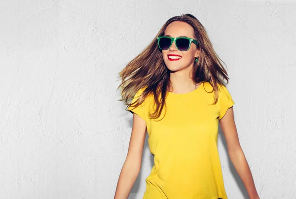 Renkli stüdyo portre, Hipster gülümseyen kız moda eller kalçalara beyaz arka plan ile. Eğlenceli olumlu genç akıllı kadın gözlük ve mükemmel ile gülümseyen renkli sarı tişört.