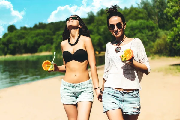 Duas meninas gêmeas hipster na moda legal com coquetéis na praia desfrutando de férias em uma ilha tropical, corpo bronzeado perfeito, pele saudável, desgaste casual sexy elegante, biquíni, gêmeos morena em óculos de sol — Fotografia de Stock
