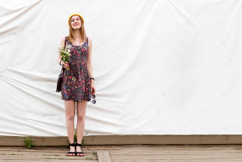 Beautiful young summer woman standing full length in a summer dress with flowers on a wooden floor on a white cloth background with copyspace