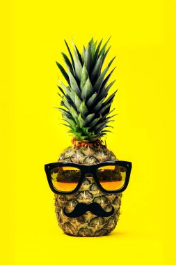 Moda ananas güneş gözlüğü ve bıyığı ile sarı arka plan üzerinde eğlenceli. Tatil ve seyahat kavramı.