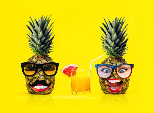 Güneş gözlüğü ve taze tropikal meyve sarı arka plan üzerinde ile kokteyl bıyıklı iki eğlenceli moda ananas. Karı ve koca. Erkek ve kız. Tatil ve seyahat gezi kavramı.