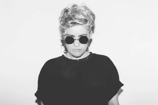 Stylish fashion sexy blonde bad girl in a black t-shirt and rock sunglasses. Dangerous rocky emotional woman. white toned. background, not isolated — Stock Photo, Image