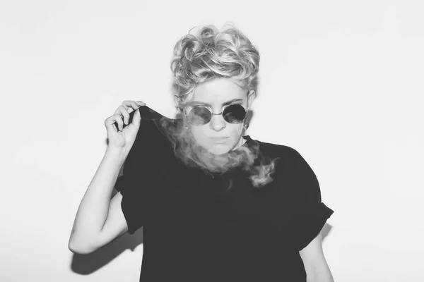 Stylish fashion sexy blonde bad girl in a black t-shirt and rock sunglasses. Dangerous rocky emotional woman. white toned. background, not isolated — Stock Photo, Image