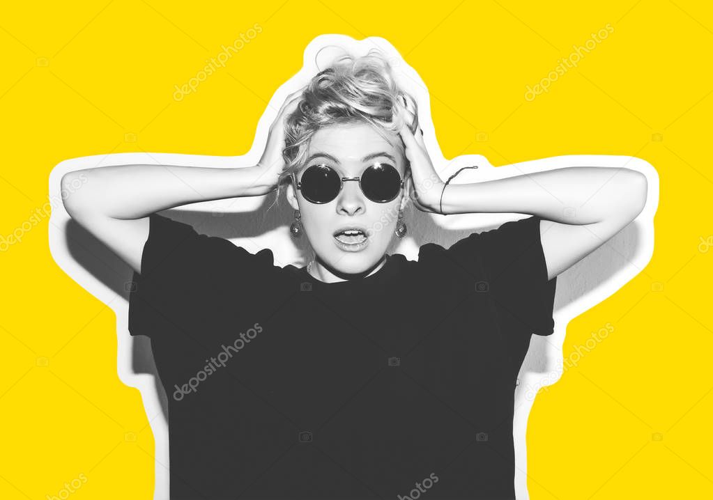 Stylish fashion blonde with short hair colorful collage. Crazy girl in a black t-shirt and rock sunglasses scream holding her head. Rocky emotional woman. white toned. yellow background, not isolated