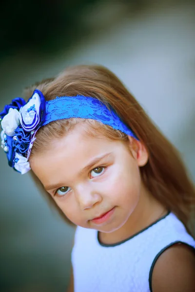 Portrait of a child in a blue headband decorated with flowers. — Stock Photo, Image