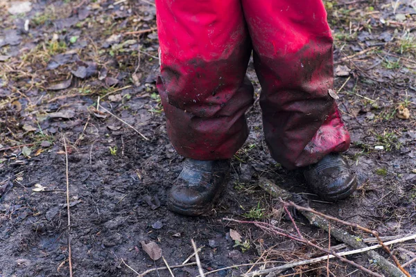 Ноги ребенка в грязных комбинезонах и пятнах обуви, стоящие на земле . — стоковое фото
