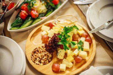 Bir ziyafette restoranda peynir tabağı. Aperatifli masa ayarları. Dilimlenmiş peynirli ahşap tepsi