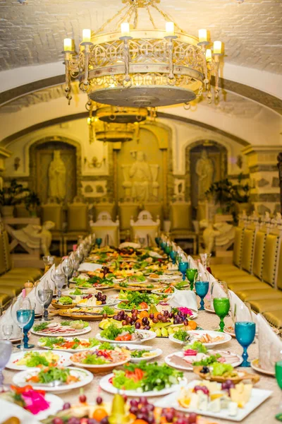 Splendidamente servito tavolo per banchetti in ristorante. Tovaglioli bianchi e bicchieri di vino blu e verde sul tavolo. Un certo numero di vecchie sedie sul caffè per Cristmas — Foto Stock