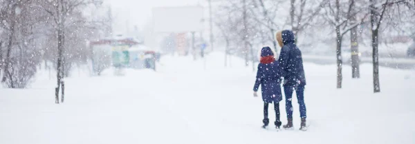 Абстрактні розмиті люди силуети ходять по засніженій вулиці взимку. Важкі снігопади в місті. Розмите зображення матері і даустера . — стокове фото